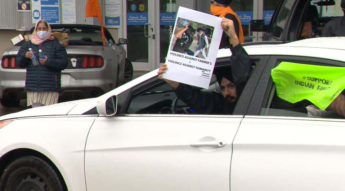 A demonstrator holds up a photo of one of the protests that turned violent in India during a car rally in Halifax on Saturday, Dec. 5, 2020.