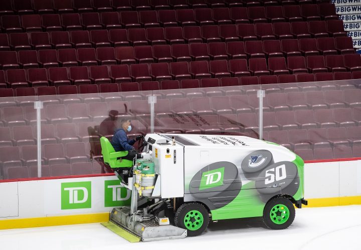 A Rogers Arena staff member wears a face mask while driving an ice resurfacing machine during the Vancouver Canucks NHL hockey team's training camp, in Vancouver, on Monday, July 13, 2020. 