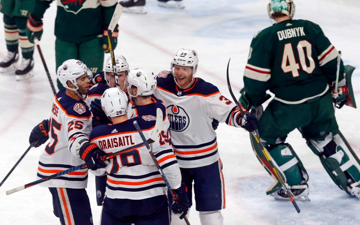 Edmonton Oilers' Leon Draisaitl, back to camera, of Germany, is congratulated by teammates after his power-play goal against Minnesota Wild goalie Devan Dubnyk, right, during the third period of an NHL hockey game Thursday, Feb. 7, 2019 in St. Paul, Minn. At left is Oilers' Darnell Nurse, who scored a first-period goal. The Oilers won 4-1;(AP Photo/Jim Mone).