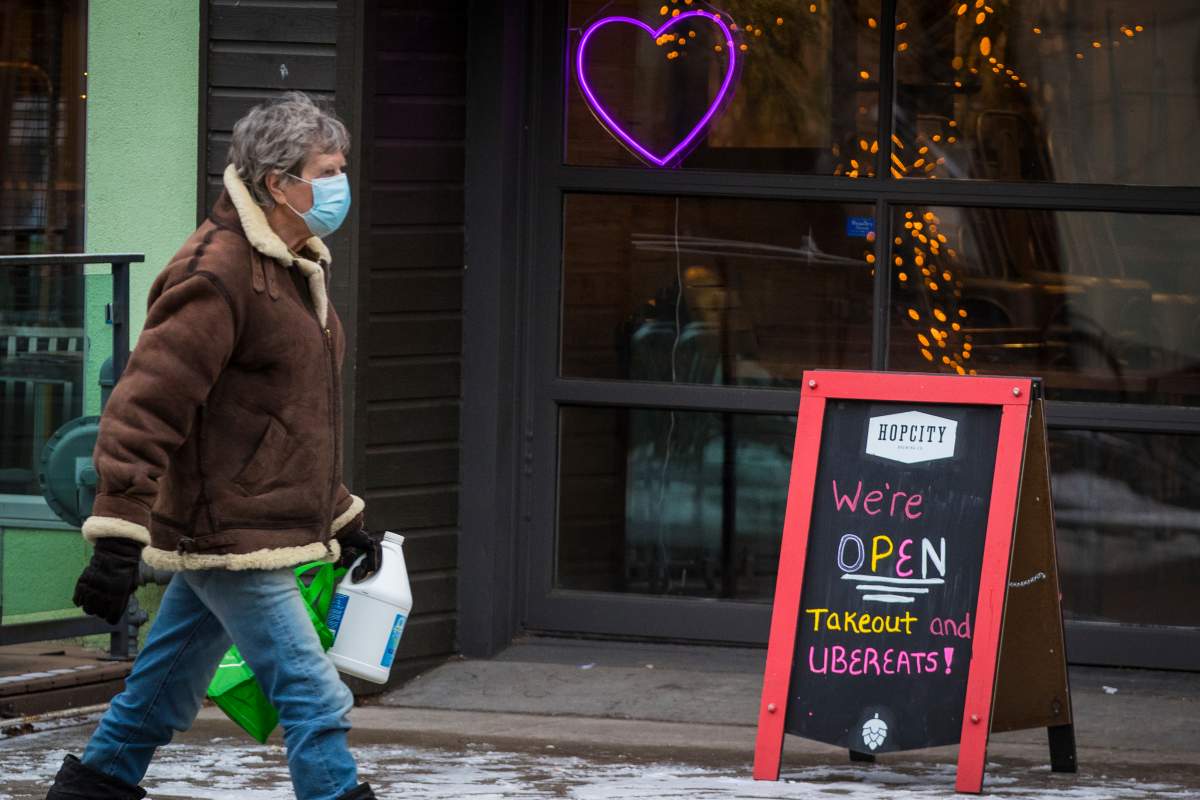 A person wears a disposable mask while walking past a restaurant that offers take-out and ubereats in Kingston, Ontario on Wednesday, December 30, 2020, as the COVID-19 pandemic continues across Canada and around the world. 