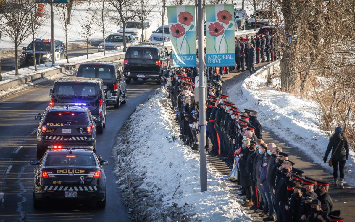 Police vehicles escort the body of Calgary Sgt. Andrew Harnett from the medical examiner’s office to a funeral home as police officers and citizens line Memorial Drive in Calgary, Alta., Tuesday, Jan. 5, 2021.