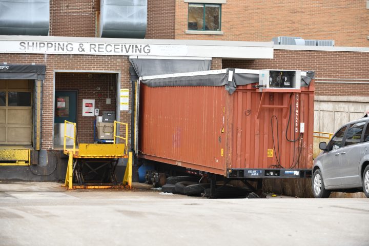 A grey minivan belonging to a local funeral home parks in front of a storage container that’s been converted into a temporary morgue at the rear of Windsor Regional Hospital Met Campus in Windsor, Ont., Wednesday, January 6, 2021. 