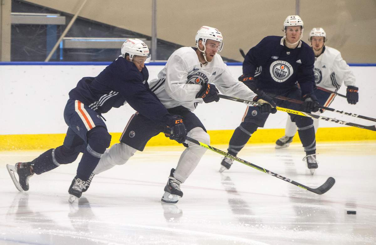 Connor McDavid (97) and Caleb Jones (82) battle for the puck during a scrimmage at the Edmonton Oilers training camp in Edmonton, Alta., on Thursday January 7, 2021. THE CANADIAN PRESS/Jason Franson.