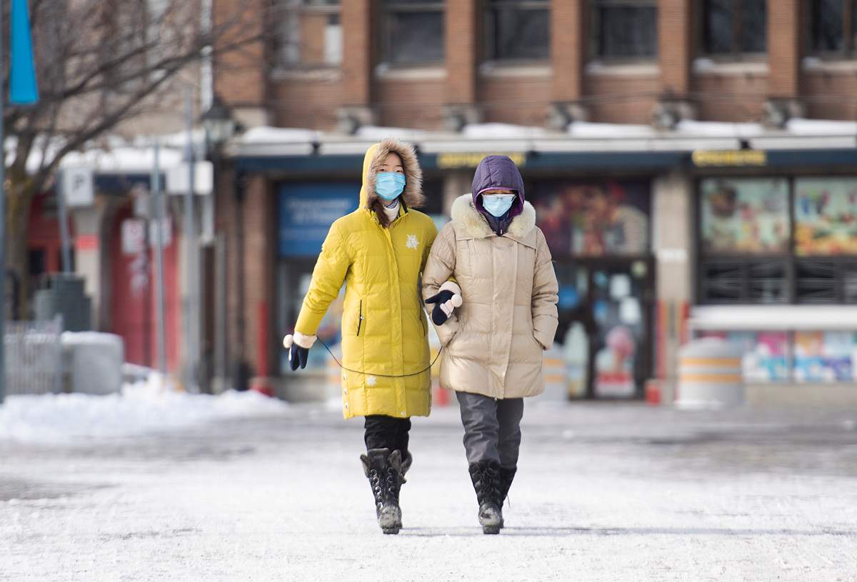 People wear face masks as they walk in the Old Port in Montreal, Sunday, January 10, 2021, as the COVID-19 pandemic continues in Canada and around the world. 