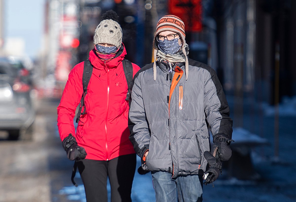 People wear face masks as they walk along a street on a cold winter day in Montreal, Sunday, Jan. 24, 2021, as the COVID-19 pandemic continues in Canada and around the world. 