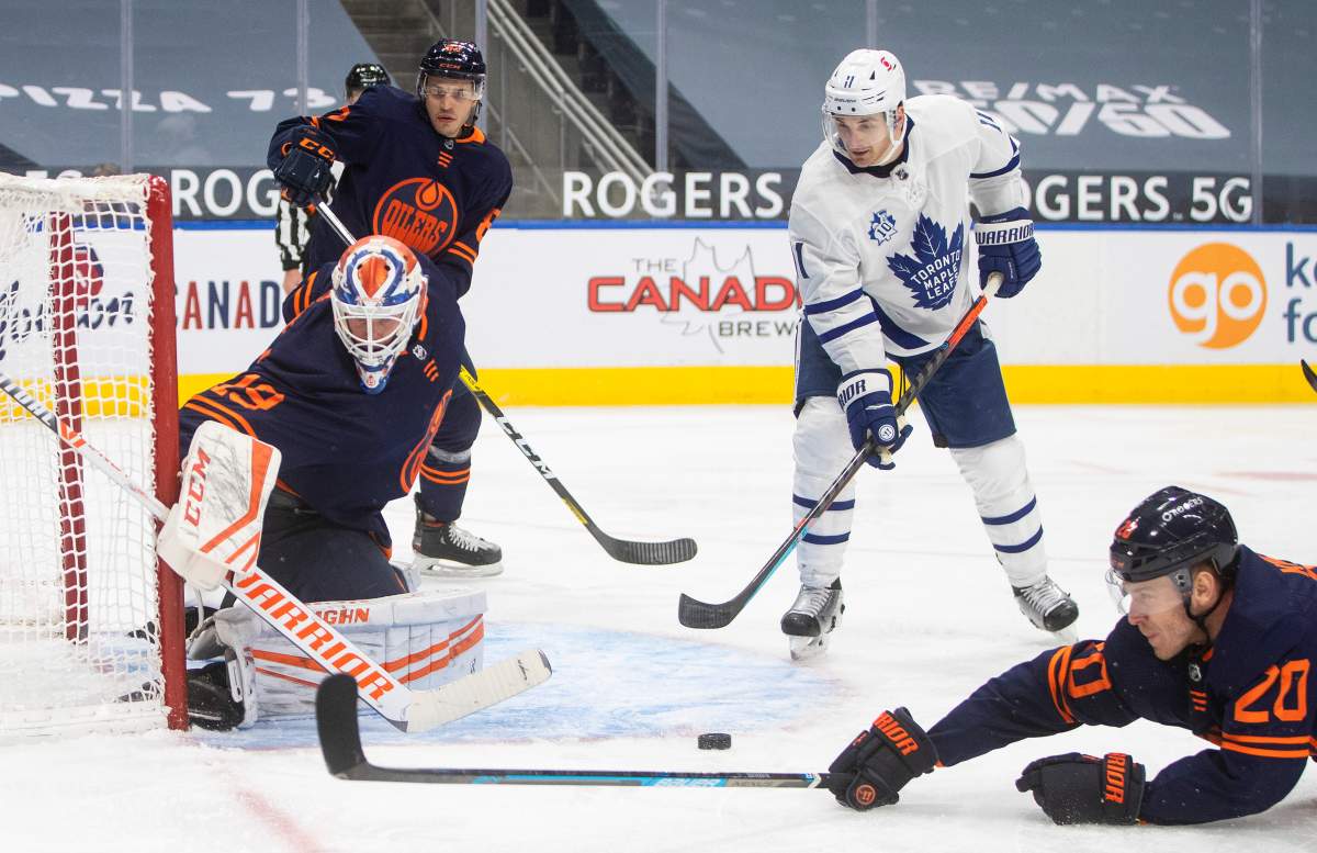 Edmonton Oilers' goalie Mikko Koskinen (19) makes the save as Toronto Maple Leafs' Zach Hyman (11) and Oilers' Slater Koekkoek (20) look for the rebound during third period NHL action in Edmonton on Thursday, January 28, 2021. THE CANADIAN PRESS/Jason Franson.