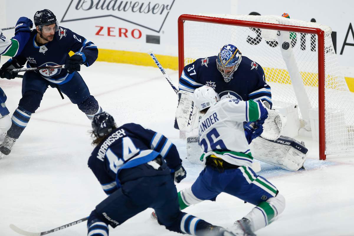 Winnipeg Jets goaltender Connor Hellebuyck (37) stops the shot from Vancouver Canucks' Nils Hoglander (36) during first period NHL action in Winnipeg on Saturday, January 30, 2021.