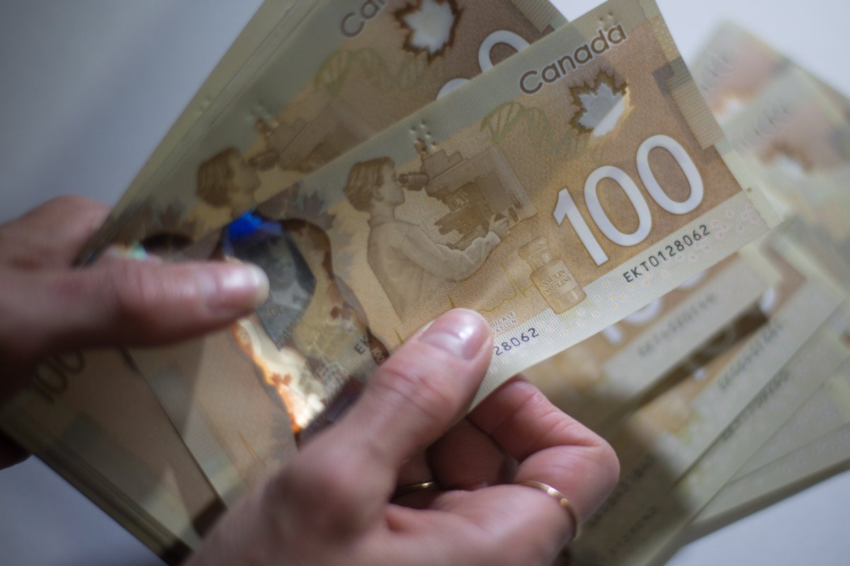 Canadian $100 bills are counted in Toronto, Feb. 2, 2016. Peterborough police warn that fake bills are circulating in the area.