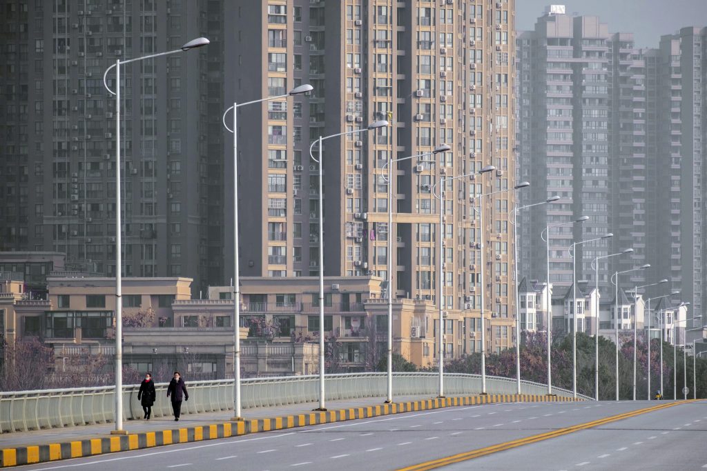 FILE – In this Jan. 28, 2020, file photo, people wearing face masks walk down a deserted street in Wuhan in central China\’s Hubei Province. (AP Photo/Arek Rataj, File)