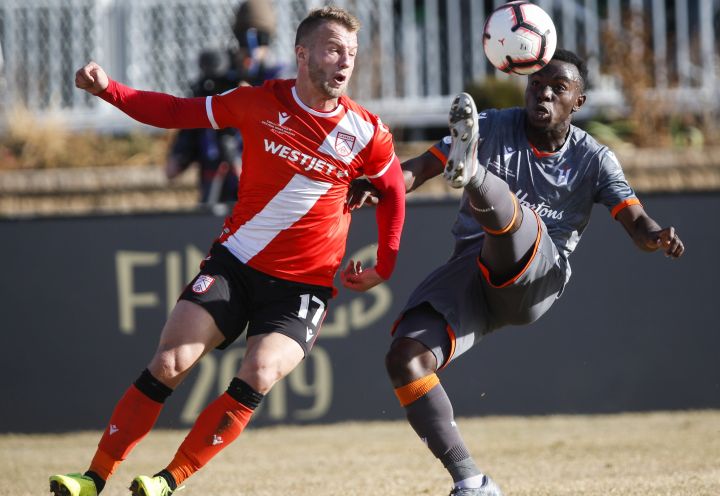 Hamilton Forge's Kwame Awuah, right, kicks the ball as Calgary Cavalry's Nico Pasquotti looks on during Canadian Premier League soccer finals action in Calgary, Alta., Saturday, Nov. 2, 2019.