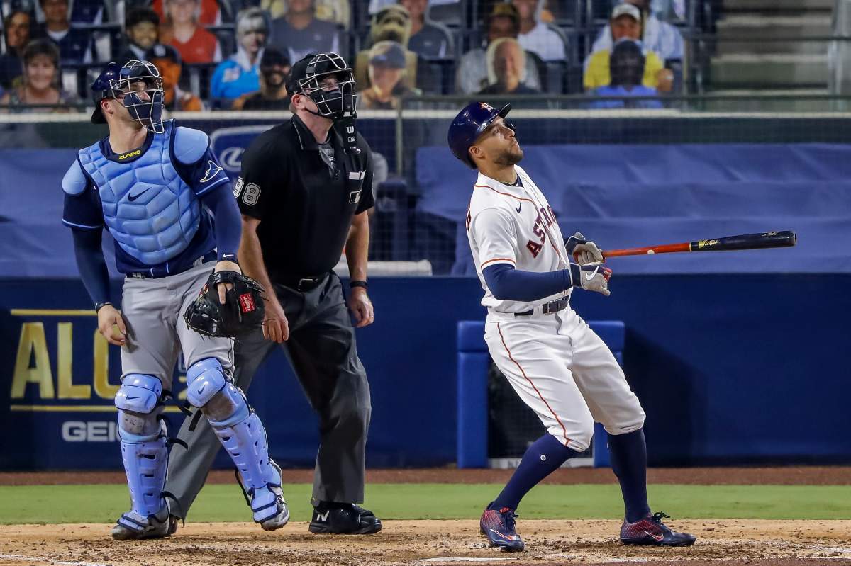 Houston Astros center fielder George Springer (R) hits a two-run home run as umpire Chris Conroy (C) and Tampa Bay Rays catcher Mike Zunino (L) look on in the fifth inning of the American League Championship Series playoff game four between the Tampa Bay Rays and the Houston Astros at Petco Park in San Diego, California, 14 October 2020.