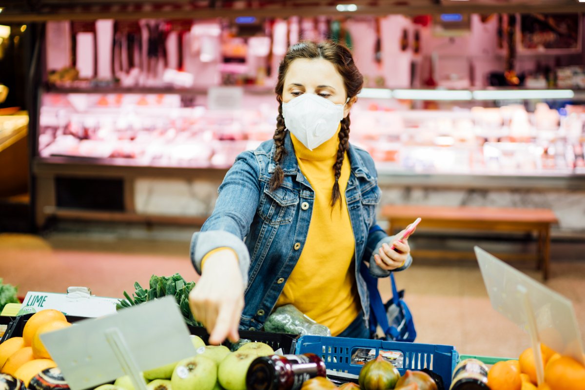 Young woman with a mask grocery shopping.