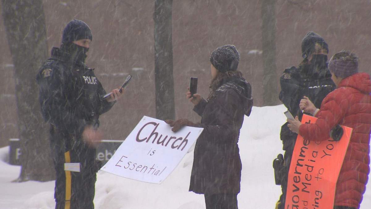 A protestor is seen interacting with a police officer at an anti-mask rally outside of city hall in Moncton, N.B.