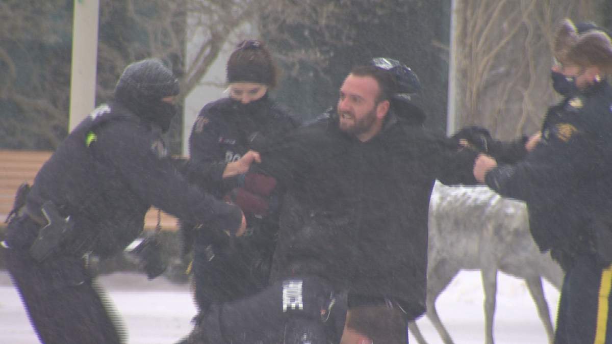 Five RCMP officers take a person into custody at an anti-mask and COVID-19 protest outside city hall in Moncton on Jan. 24.