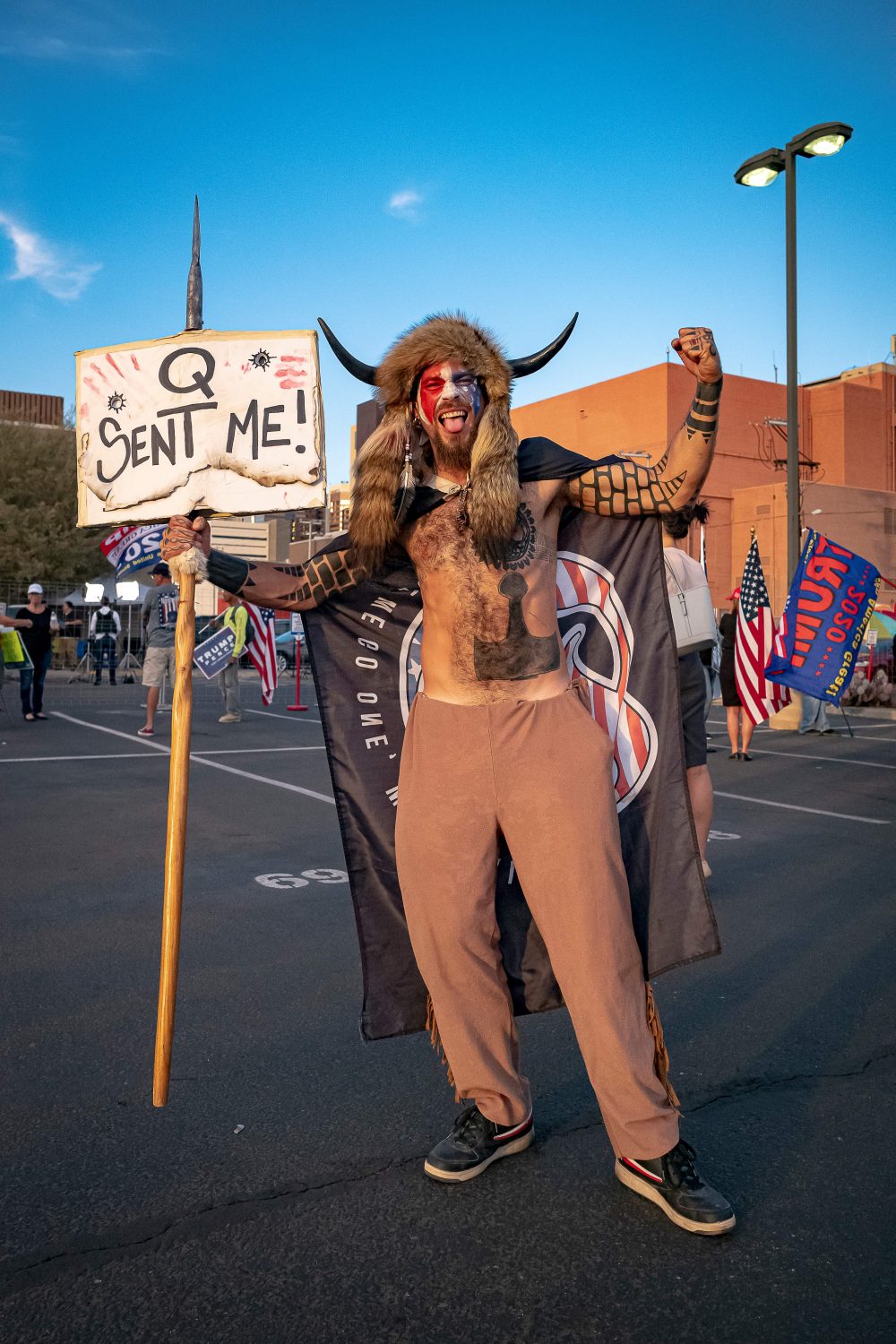 Jake Angeli, 33, a.k.a Yellowstone Wolf, from Phoenix, holds a QAnon sign, as he presents himself as a shamanist and consultant for the Trump supporters gathered in front of the Maricopa County Election Department where ballots are counted after the U.S. presidential election in Phoenix on Nov. 5, 2020.