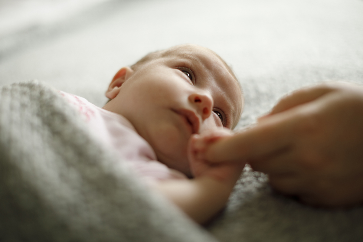 A newborn baby holding its mother's hand.