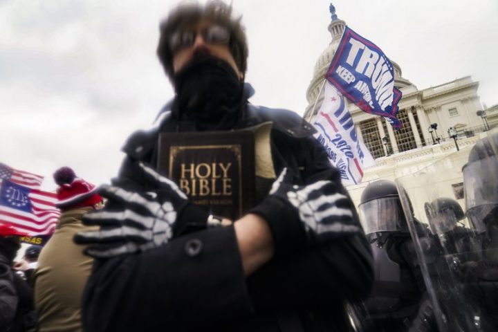FILE – In this Wednesday, Jan. 6, 2021 file photo, a man holds a Bible as Trump supporters gather outside the Capitol in Washington.