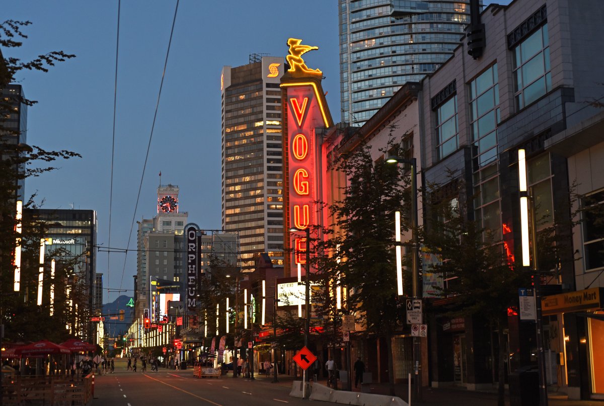 Buildings and stores including the Vogue theatre light up Granville Street at dusk in downtown Vancouver, British Columbia on August 26, 2020. 