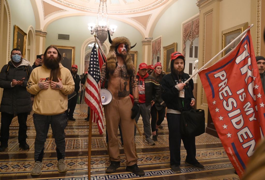 Supporters of U.S. President Donald Trump enter the U.S. Capitol on Jan. 6, 2021. A work ID badge is visible on the man to the right with the flag.