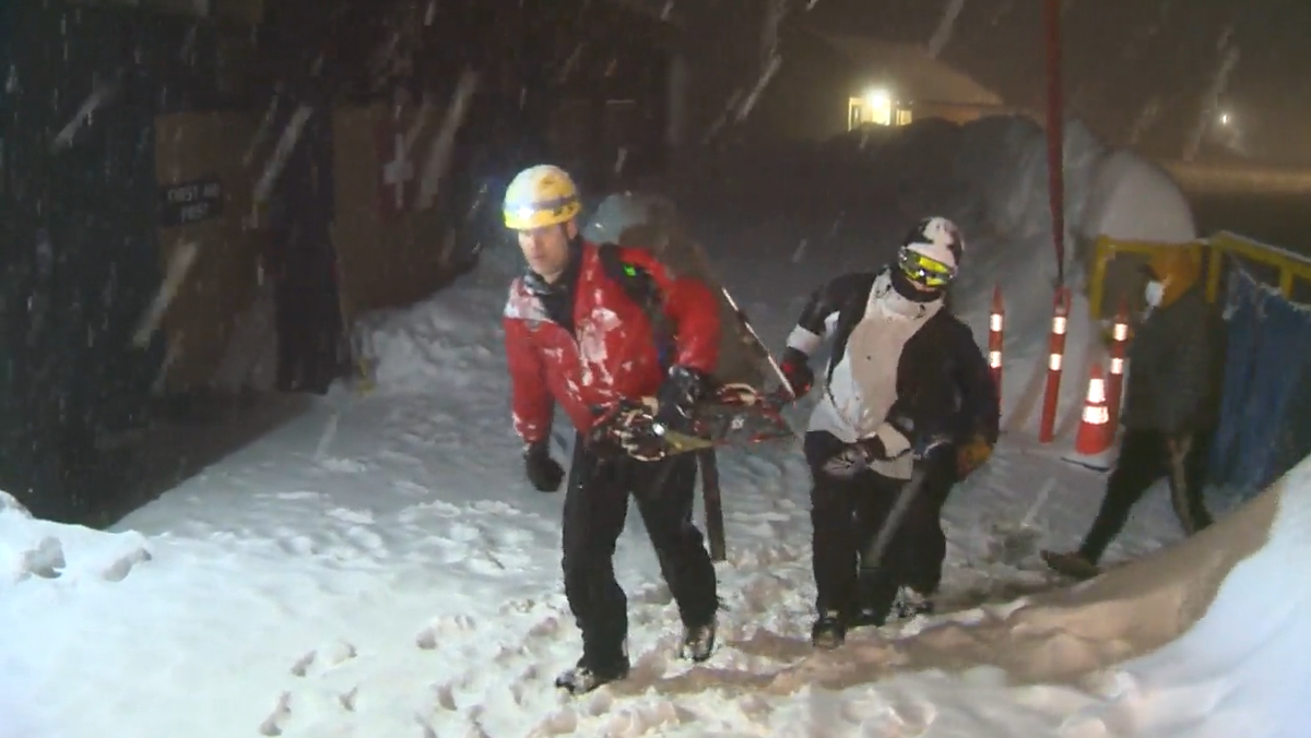 North Shore Rescue volunteers escort a pair of rescued out-of-bounds snowboarders to safety Friday night. 