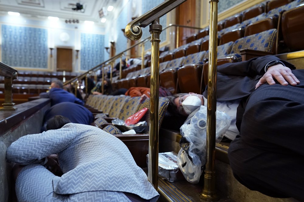 People shelter in the House gallery as protesters try to break into the House Chamber at the U.S. Capitol on Wednesday, Jan. 6, 2021, in Washington.