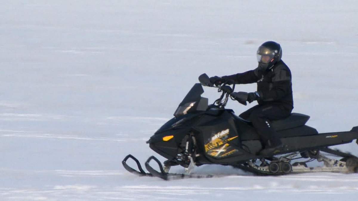 A snowmobile operating on a snow and ice covered lake.