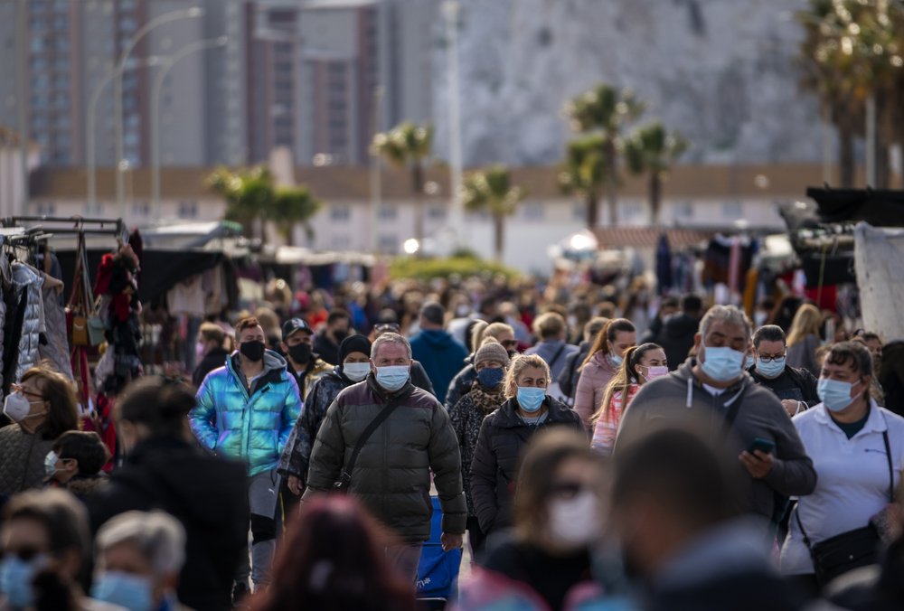 People wearing face masks walk along the stalls of a weekly market in the Spanish city of La Linea. 