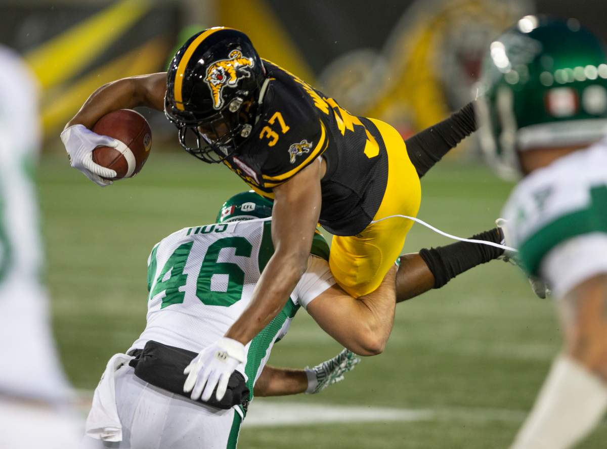 Hamilton Tiger-Cats Frankie Williams goes high over the tackle of Saskatchewan Roughriders Jorgen Hus during second half CFL football game action in Hamilton, Ont. on Thursday, June 13, 2019. THE CANADIAN PRESS/Peter Power.