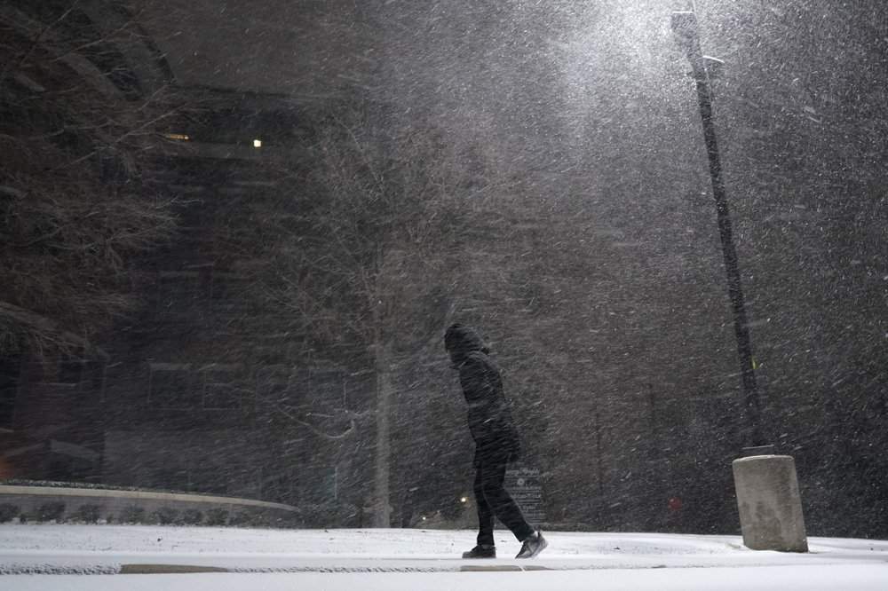 A woman walks through falling snow in San Antonio, Sunday, Feb. 14, 2021. Snow and ice blanketed large swaths of the U.S. on Sunday, prompting canceled flights, making driving perilous and reaching into areas as far south as Texas’ Gulf Coast, where snow and sleet were expected overnight.