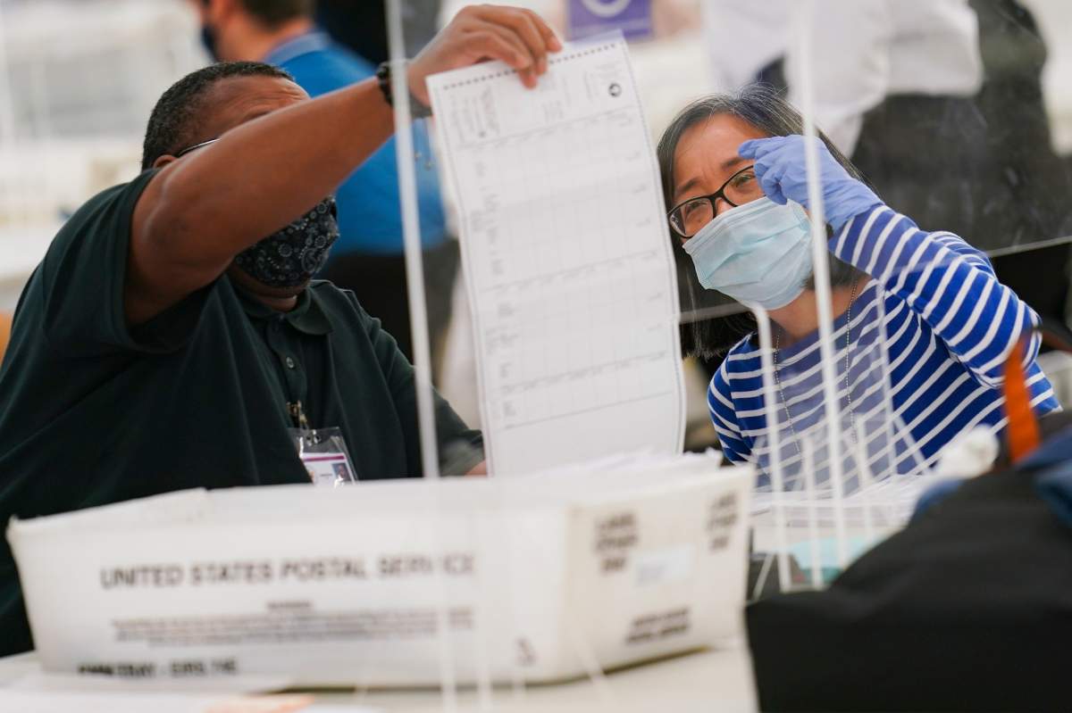 FILE - Polling workers inspect and count absentee ballots, Tuesday, Nov. 10, 2020, in New York. 