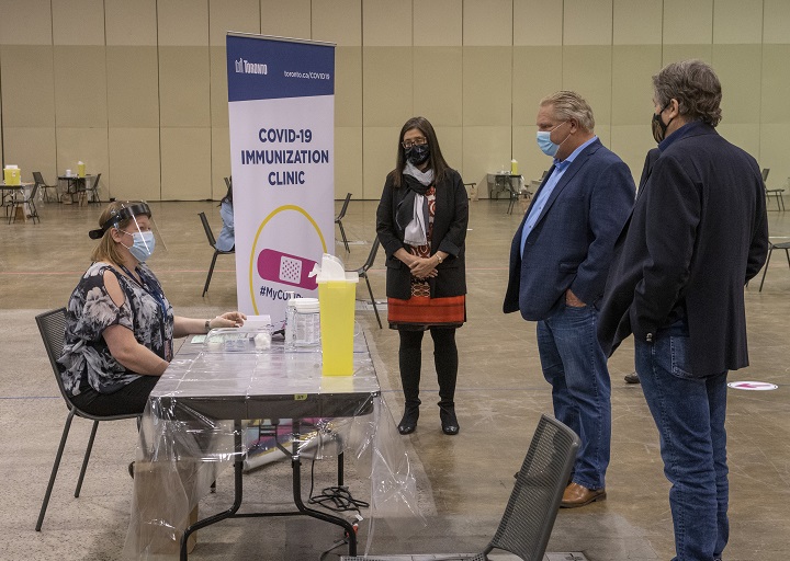 Toronto Public Health Nurse Amanda Alves, far left, greets Ontario Premier Doug Ford, centre, and Toronto Mayor John Tory, right, as they are given a tour of Toronto’s Mass Vaccination Clinic by Toronto Medical Officer of Health Dr. Eileen de Villa, centre left, on Sunday January 17, 2021.