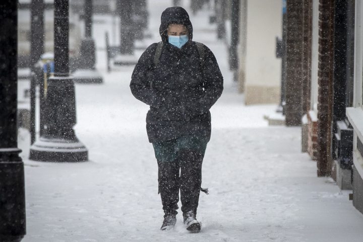 A person wears a mask during a snow squall in Kingston, Ontario on Tuesday, January 26, 2021.