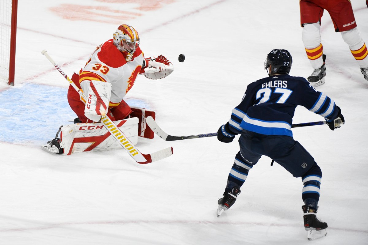 Winnipeg Jets' Nikolaj Ehlers (27) deflects a shot over Calgary Flames goaltender David Rittich (33) for a goal during first period NHL action in Winnipeg on Tuesday Feb. 2, 2021. 