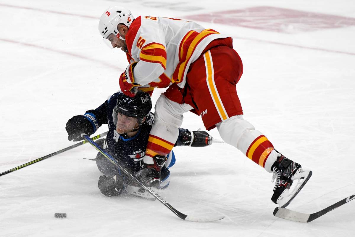 Winnipeg Jets’ Nikolaj Ehlers (27) is checked by Calgary Flames’ Mark Giordano (5) during second period NHL action in Winnipeg on Tuesday, Feb. 2, 2021.