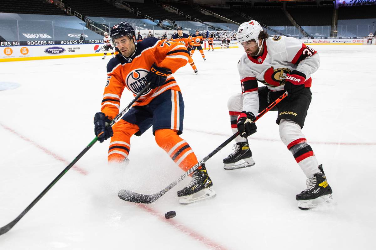 Edmonton Oilers' Evan Bouchard (75) and Ottawa Senators' Colin White (36) battle for the puck during first period NHL action in Edmonton on Tuesday, February 2, 2021. 
