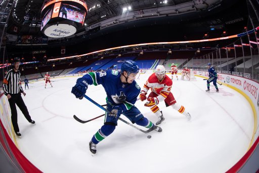 Vancouver Canucks’ Nils Hoglander (36), of Sweden, controls the puck in front of Calgary Flames’ Sean Monahan (23) during the second period of an NHL hockey game in Vancouver, on Saturday, Feb. 13, 2021.