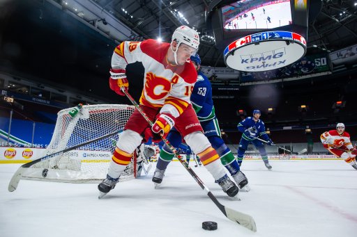 Calgary Flames’ Matthew Tkachuk controls the puck in front of Vancouver Canucks’ Bo Horvat during the second period of an NHL hockey game in Vancouver, on Saturday, Feb. 13, 2021.