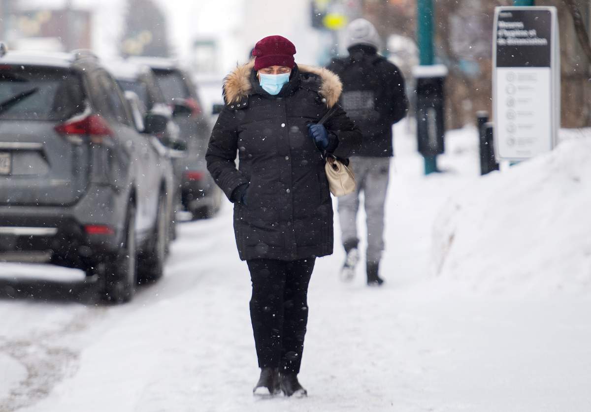A woman wears a face mask as she walks along a street in Montreal, Sunday, Feb. 14, 2021, as the COVID-19 pandemic continues in Canada and around the world. 