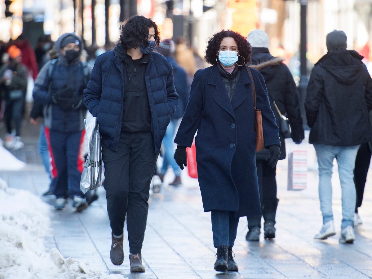 People wear face masks as they walk along a street in Montreal, Sunday, Feb. 14, 2021, as the COVID-19 pandemic continues in Canada and around the world. 