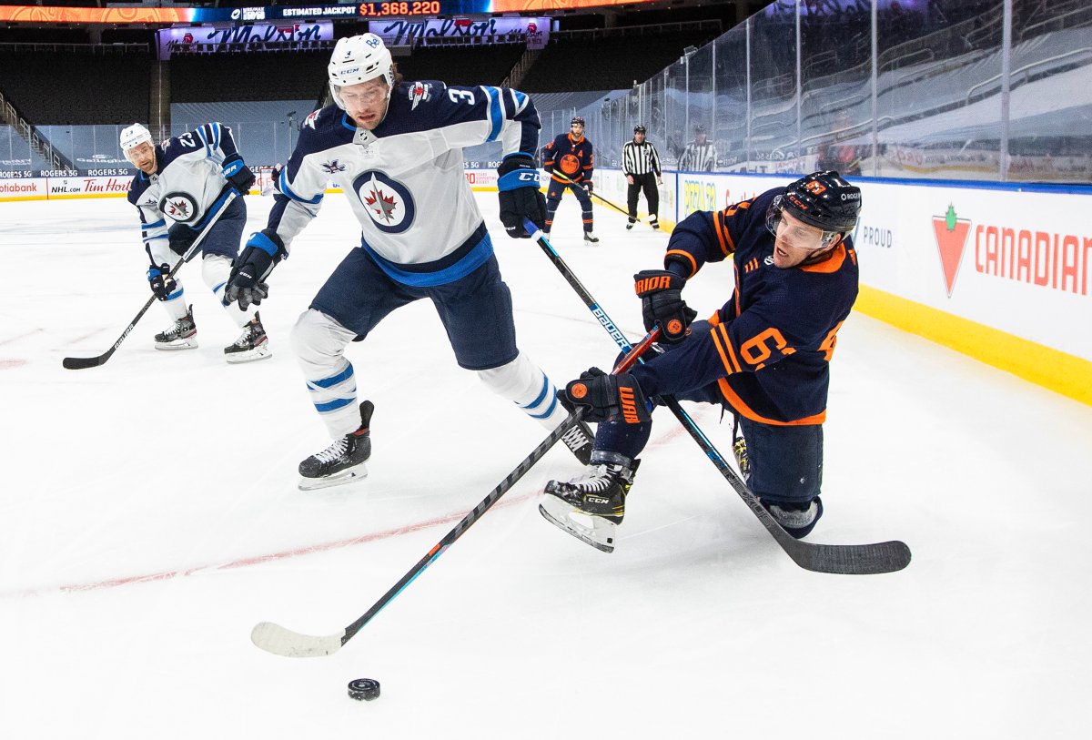 Edmonton Oilers' Tyler Ennis (63) and Winnipeg Jets' Tucker Poolman (3) battle for the puck during second period NHL action in Edmonton on Monday, February 15, 2021. 