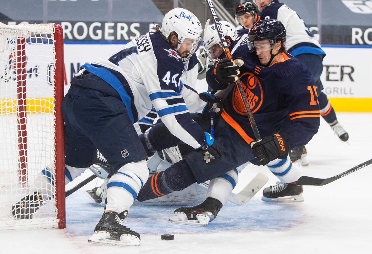 Edmonton Oilers’ Josh Archibald (15) is checked by Winnipeg Jets’ Josh Morrissey (44) during second period NHL action in Edmonton on Monday, February 15, 2021.
