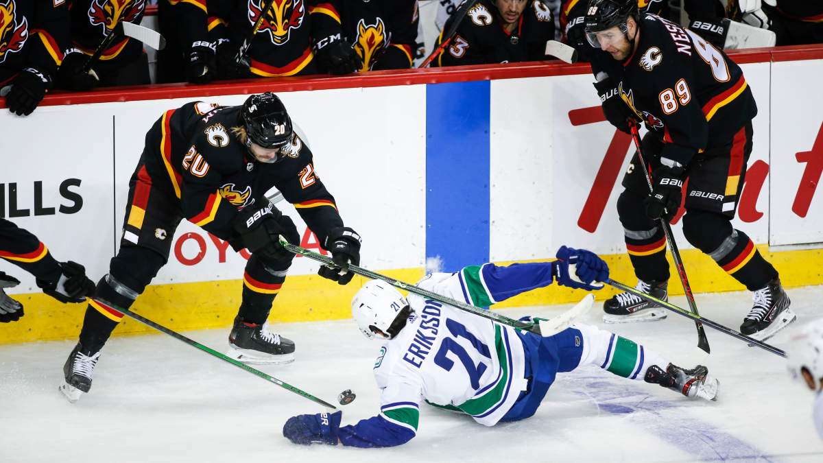 Vancouver Canucks’ Loui Eriksson, centre, is knocked to the ice by Calgary Flames’ Joakim Nordstrom, left, as Nikita Nesterov looks on during second period NHL hockey action in Calgary, Wednesday, Feb. 17, 2021.