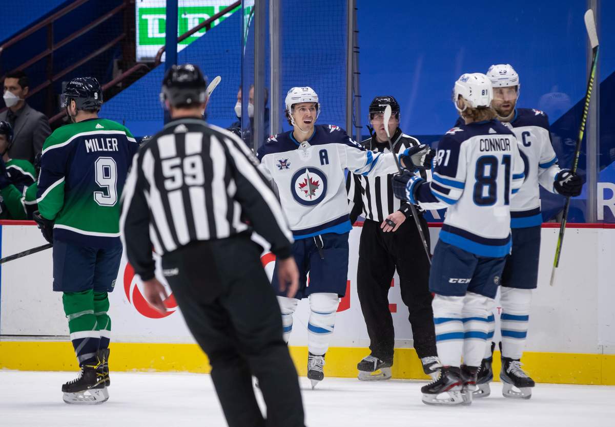 Winnipeg Jets' Mark Scheifele, back centre, Kyle Connor (81) and Blake Wheeler (26) celebrate Scheifele's goal as Vancouver Canucks' J.T. Miller (9) skates to the bench during the first period of an NHL hockey game in Vancouver, on Friday, February 19, 2021. THE CANADIAN PRESS/Darryl Dyck