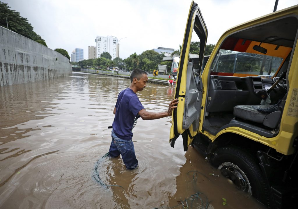A man steps out of his truck after it was stuck on a flooded toll road following heavy rains in Jakarta, Indonesia, Saturday, Feb. 20, 2021. Heavy downpours combined with poor city sewage planning often causes heavy flooding in parts of greater Jakarta. (AP Photo/Dita Alangkara).