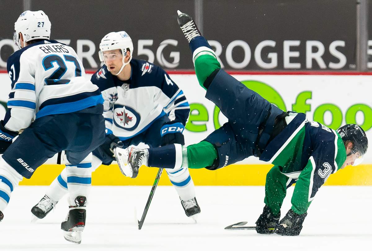 Vancouver Canucks left wing Nils Hoglander (36) fights for control of the puck with Winnipeg Jets defenceman Neal Pionk (4) during first period NHL action in Vancouver, Sunday, February 21, 2021.  