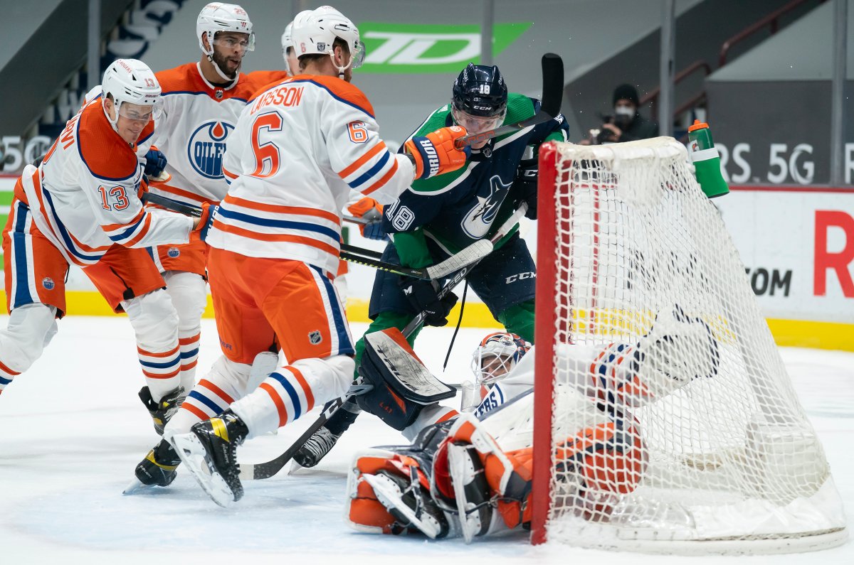 Vancouver Canucks right wing Jake Virtanen (18) tries to get a shot past Edmonton Oilers goaltender Mike Smith (41) as Oilers' Adam Larsson (6) defends during second period NHL action in Vancouver, Thursday, February 25, 2021.  THE CANADIAN PRESS/Jonathan Hayward.