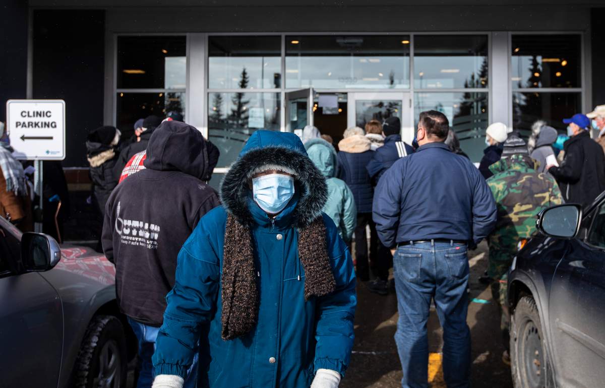 People line up outside a vaccine clinic as seniors wait to get the COVID-19 vaccine in Edmonton, Alta., on Friday, Feb. 26, 2021.