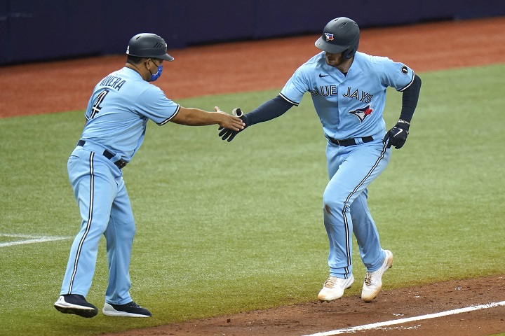 Toronto Blue Jays' Danny Jansen shakes hands with third base coach Luis Rivera (4) after Jensen hit a solo home run off Tampa Bay Rays starting pitcher Tyler Glasnow during the third inning of Game 2 of an American League wild-card baseball series Wednesday, Sept. 30, 2020, in St. Petersburg, Fla.
