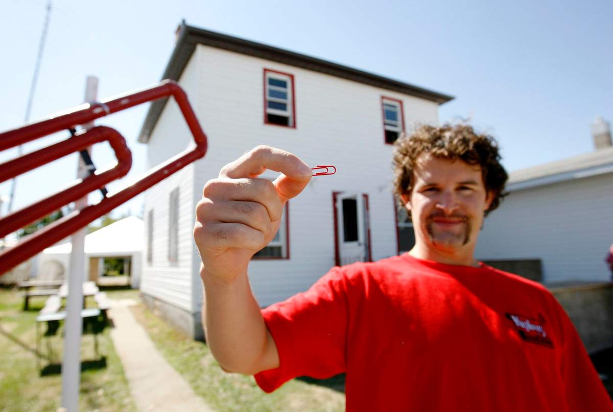 Kyle MacDonald holds up a red paper clip in front of his house in Kipling, Sask., on Friday, Sept. 1, 2006.  (CP PHOTO/Troy Fleece)