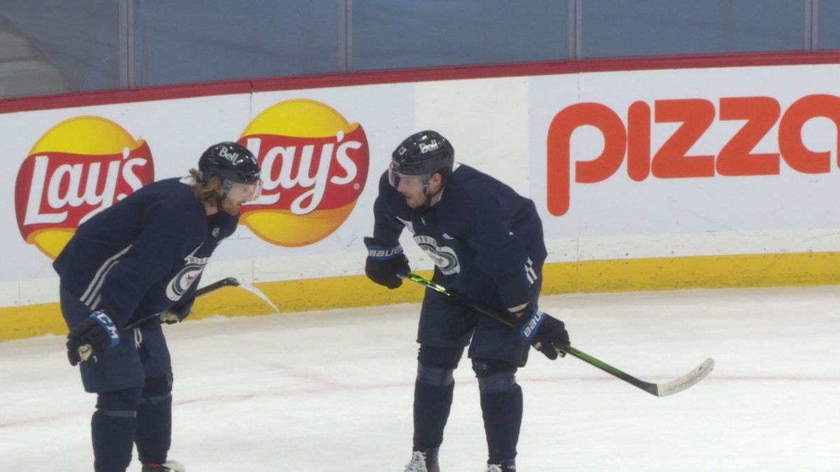 Pierre-Luc Dubois chats with new line mate Kyle Connor at practice on Sunday.